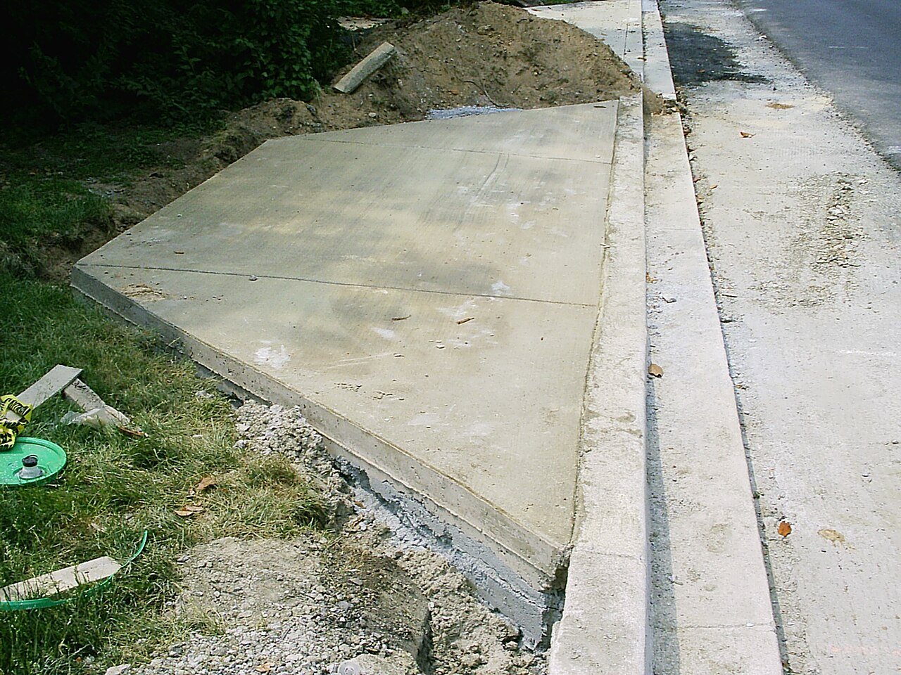 Freshly poured concrete driveway apron meeting a sloped street curb